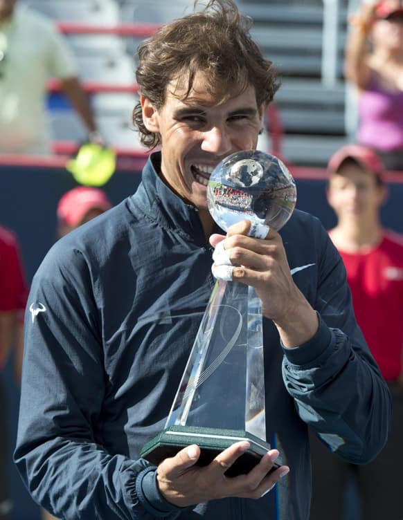 Rafael Nadal, of Spain, jokes with the trophy after defeating Canada`s Milos Raonic during the final at the men`s Rogers Cup tennis tournament final action in Montreal.