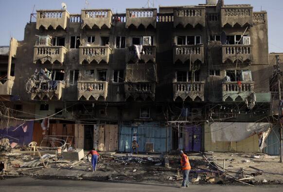 People clean up the aftermath of a car bomb attack on a convenience store in the Shaab neighborhood of Baghdad, Iraq.