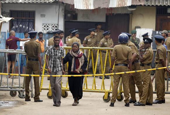 A Sri Lankan Muslim couple walks past a police barricade outside a vandalized mosque, unseen, in Colombo, Sri Lanka.