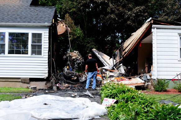Officials inspect the debris, after a small plane, piloted by Bill Henningsgaard, crashed into two homes Friday in East Haven, Conn. Four people were killed in the incident.