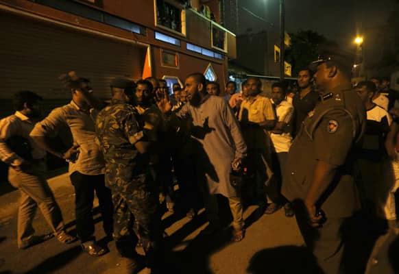 Sri Lankan police officers attempt to disperse Muslims waiting out side a vandalized mosque in Colombo, Sri Lanka.