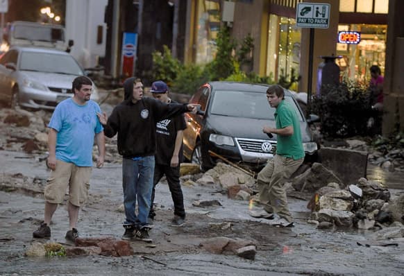 People look in disbelief as they see the damage on Park Avenue after a flash flood ripped through downtown, in Manitou, Colo.