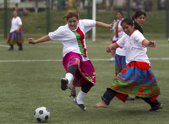 Women dressed in traditional Andean skirts and wearing sandals play a game at a soccer championship in Lima, Peru.