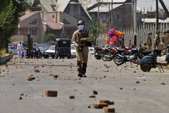 An Indian paramilitary soldier walks on a road scattered with bricks and stones thrown by Kashmiri protesters during a clash between them in Srinagar.