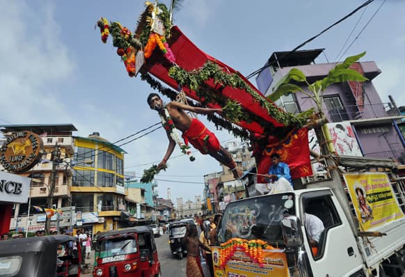 A truck carries a Sri Lankan Hindu devotee hanging with iron hooks pierced into his back as a ritual during a Hindu temple festival in Colombo.