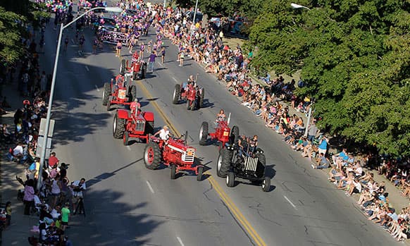 Old tractors cruse down Grand Avenue during the Iowa State Fair parade in East Village of Des Moines, Iowa.