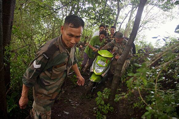 Indian army personnel help carry a scooter as they assist in the evacuation of a village in Dharmsala.