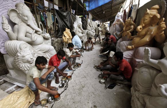 Workers eat food while taking a break from preparing idols of God Ganesh for sale for the upcoming Ganesh Chaturthi festival at a workshop in Mumbai.