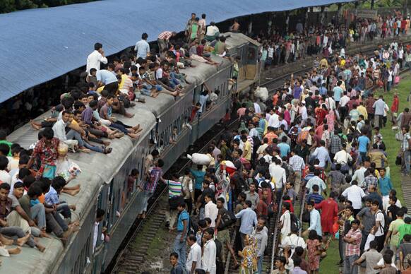 Bangladeshi passengers sit on the roof of an overcrowded train as others wait on the platform as they try to reach their homes to celebrate Eid al-Fitr in Dhaka.
