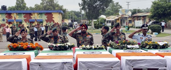 Indian army chief General Bikram Singh, center, and other army officers salute next to the coffins of Indian soldiers allegedly killed by Pakistani soldiers during a wreath laying ceremony in Jammu.