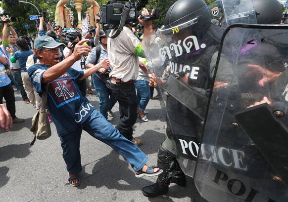 An anti-government protester scuffles with Thai riot police in Bangkok, Thailand. Thai lawmakers began debating a controversial bill that many people fear could pave the way for an ousted prime minister to return.