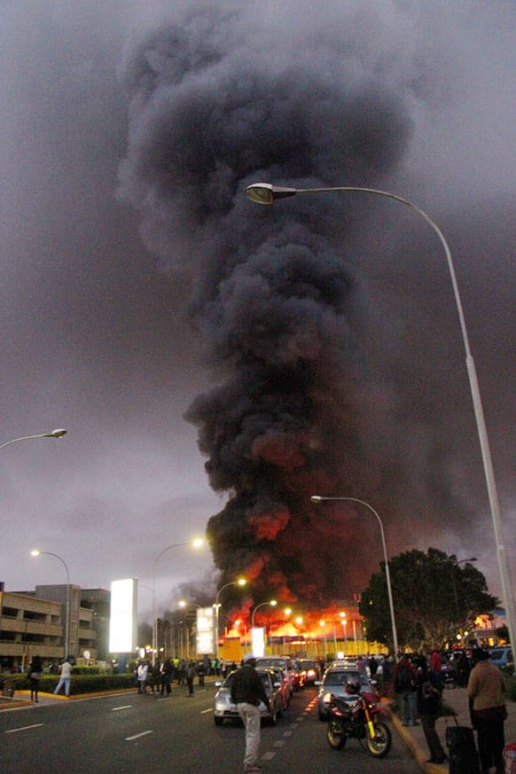 People watch dense black smoke billowing from the Jomo Kenyatta International Airport in Nairobi, Kenya. Firefighters are battling a large blaze raging at Kenya`s main international airport.