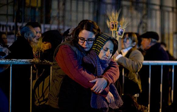 Catholic faithful embrace as they wait outside Saint Cayetano Basilica for the temple to open at midnight in Buenos Aires, Argentina.