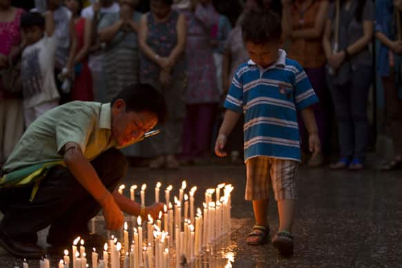 A Tibetan exile places candles during a candle light vigil as a young boy watches in New Delhi. A Tibetan monk died Tuesday after setting himself on fire in Nepal`s capital in what is believed to be the latest protest against Chinese rule over Tibet.