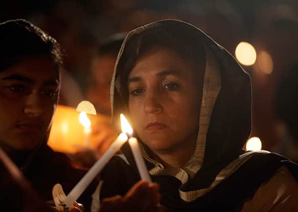 People light each others candles during a candlelight vigil at the Sikh Temple of Wisconsin to mark the one-year anniversary of the shooting rampage that left six dead, in Oak Creek, Wis.