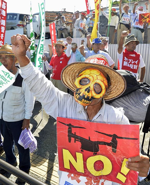 Protesters chant slogans against Monday`s accident of a US military helicopter crash and planned additional deployment of Osprey transport aircraft in front of a gate to US.