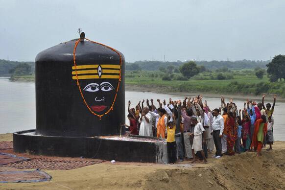 Devotees raise their hands and chant religious slogans as they worship newly installed