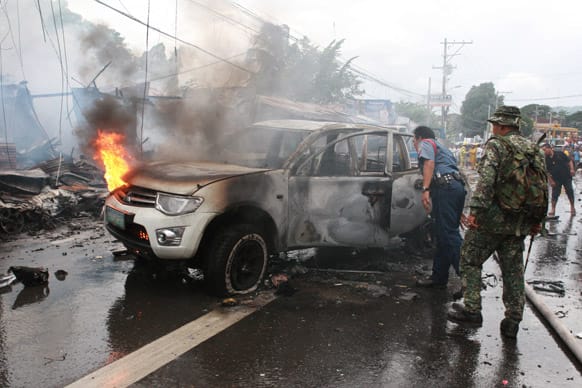 Police and military personnel inspect a burnt vehicle after a powerful bomb exploded in Cotabato city, southern Philippines.
