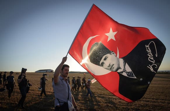 A man walks with a national flag with an image of Turkey`s founder Kemal Ataturk outside the Silivri jail complex outside the Silivri jail complex in Silivri, Turkey.