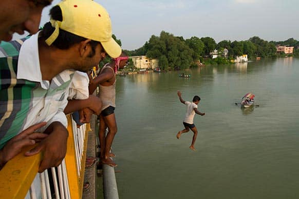A man jumps to swim from a bridge across the River Ganges which is flooded after heavy monsoon rains in Allahabad.