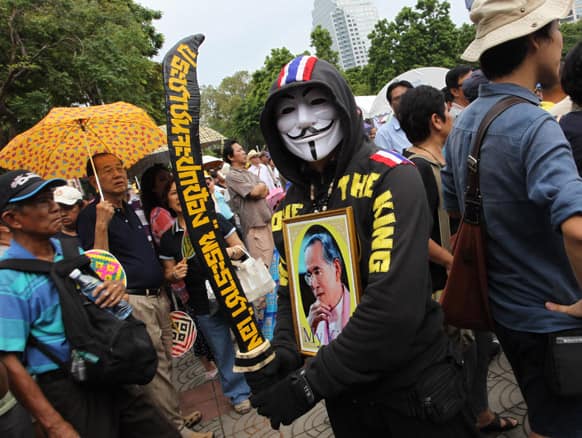 An anti-government protester wearing a mask and the photo of King Bhumibol Adulyadej on his chest, takes part in a rally outside a park in Bangkok, Thailand.