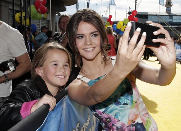 Actress Maia Mitchell, takes a photo with fan Violette Greer as she walks the red carpet for the premiere of her Disney Channel original movie