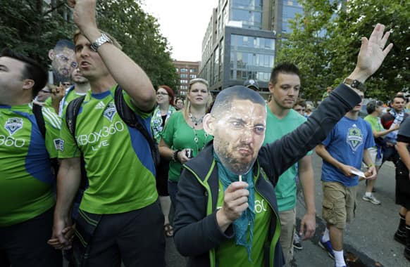 Seattle Sounders fans carry photos of Clint Dempsey, captain of the US Mens National Team, as they take part in the traditional