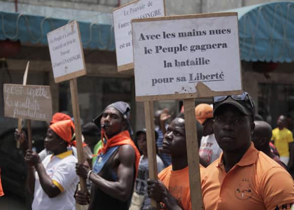 Opposition protestors carry signs reading