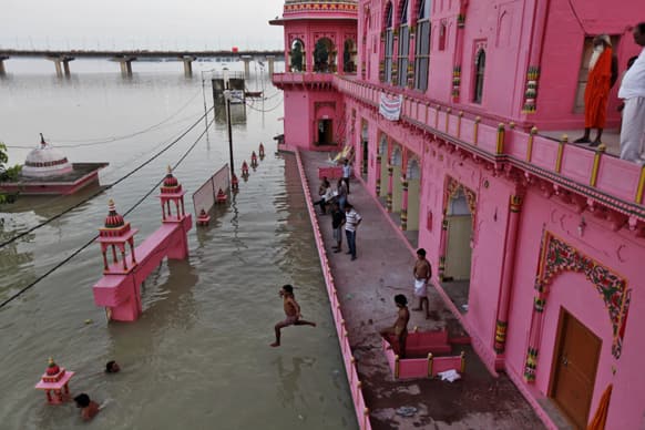 A man jumps to cool off from a residential building partly submerged in the flooded River Ganges after heavy monsoon rains in Allahabad.