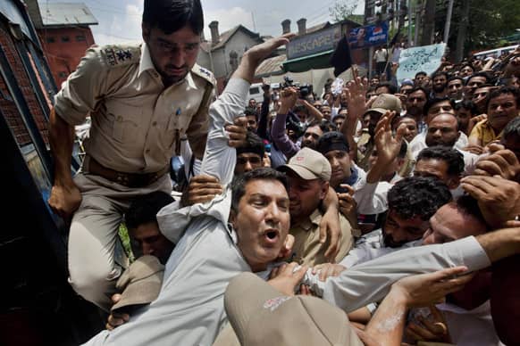 A Kashmiri government employee, front, shouts slogans as he is detained during a protest in Srinagar.