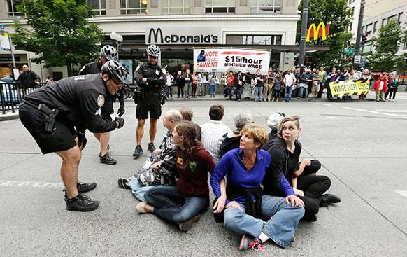 A Seattle police officer leans in to explain the arrest procedure to a group of eight protesters blocking a downtown intersection in Seattle.
