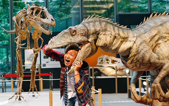 Japanese actor Takeshi Tsuruno performs with a replica of the Velociraptor during the opening ceremony of the dinosaurs exhibition in Tokyo.