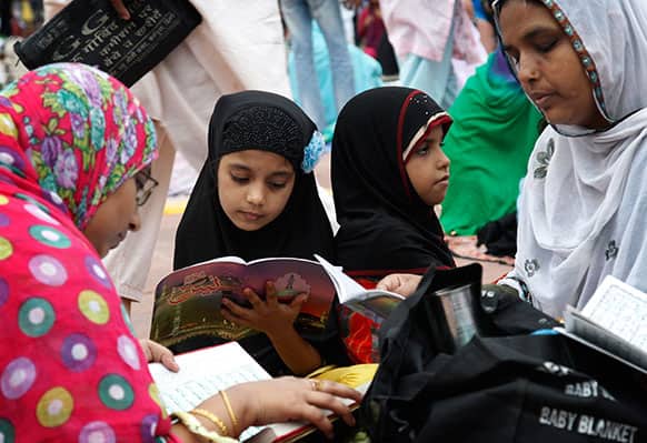 A Muslim family read holy scriptures as they all wait to break their Ramadan fast at Jama Mosque, in New Delhi.
