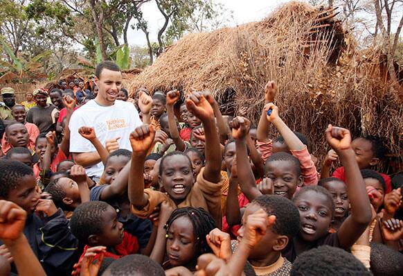 In this photo provided by United Nations Foundation, NBA superstar Stephen Curry celebrates the arrival of mosquito nets with children in the Nyarugusu Refugee Camp in Tanzania, during a Nothing But Nets trip to distribute anti-malaria bed nets.