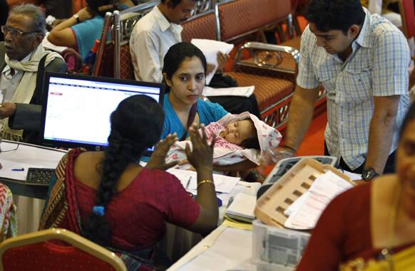 A taxpayer holds her baby as she listens to an official before filing her income returns for the previous financial year at a special counter set up by the Income Tax department in Bangalore.