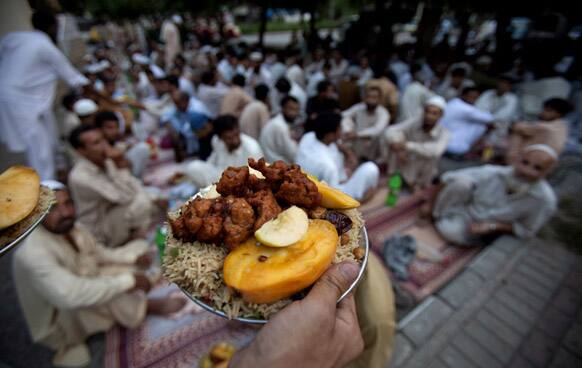 Pakistani volunteers provide food to people waiting for Iftar, the meal that breaks the day`s fast, during the holy month of Ramadan in Islamabad, Pakistan.