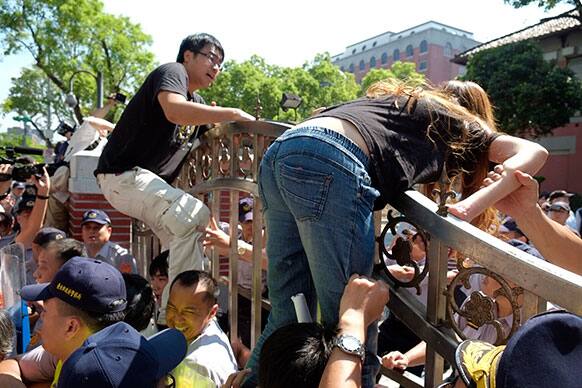 Student protesters scale the gates of the legislature in defiance of Taiwan`s latest trade pact agreement with China, in Taipei, Taiwan.