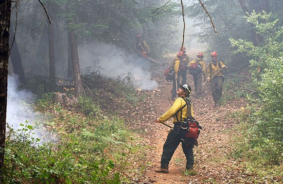 Oregon Woods crew leader Chuck Watkins, front, monitors a small section of the Douglas Complex Fire as his crew clears a break line outside Glendale, Ore.
