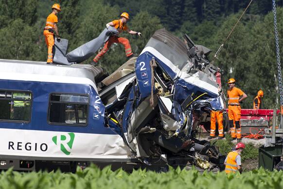 Swiss Federal Railways employees cover one of the trains after the collision, in Granges-pres-Marnand in Western Switzerland. One of the train drivers died and several passengers were injured in the accident.