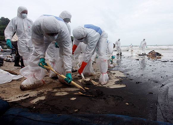 Workers use shovels to remove crude oil during a clean up operation on the beach of Prao Bay on Samet Island in Rayong province eastern Thailand.