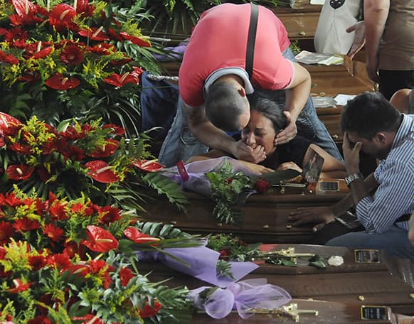 People mourn their loved ones amongst the coffins of some of the victims of Sunday`s bus crash prior to the start of their funeral service, in Pozzuoli, near Naples, southern Italy.