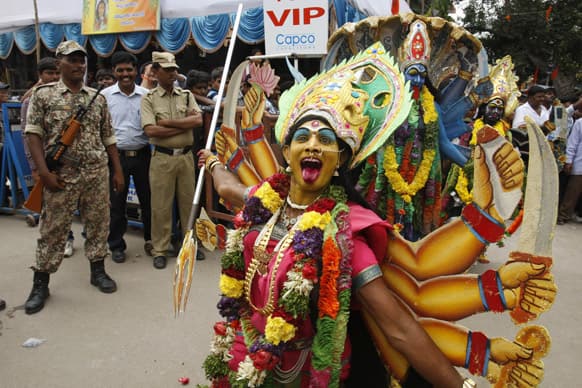 Security men watch artists dressed like Hindu goddess Kali perform during Bonalu festival in Hyderabad.