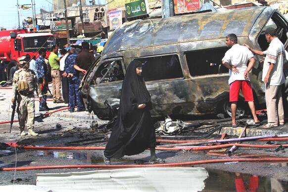 People and security forces inspect the site of a car bomb explosion in Basra, Iraq. A wave of over a dozen car bombings hit central and southern Iraq during morning rush hour on Monday, killing scores of people in the latest coordinated attack by insurgents determined to undermine the government.