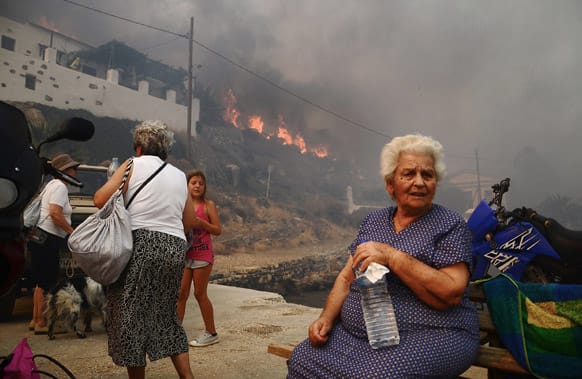 Inhabitants and holidaymakers evacuate the village of Megalo Livadi on Greece`s Aegean island of Serifos as a wildfire rages.