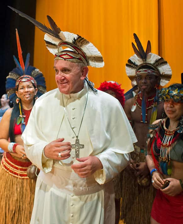 Pope Francis wears an indigenous headdress given to him by Ubirai Matos from the Pataxo tribe, not seen, after the pontiff spoke at Rio`s Municipal Theater to an audience mostly made up of Brazil`s political, business and cultural elite in Rio de Janeiro, Brazil.