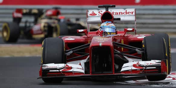 Ferrari driver Fernando Alonso of Spain steers his car ahead of Lotus driver Kimi Raikkonen of Finland during the qualifying session at the Hungaroring racetrack near Budapest, Hungary.