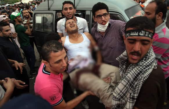 Supporters of Egypt`s ousted President Mohammed Morsi carry an injured man to a field hospital following clashes with security forces at Nasr City, where pro-Morsi protesters have held a weekslong sit-in, in Cairo, Egypt.