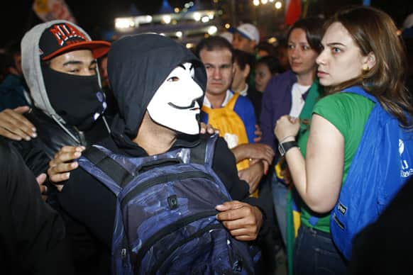 Anti-government demonstrators, left, walk past pilgrims attending the Way of the Cross service on the Copacabana beachfront, in Rio de Janeiro, Brazil.