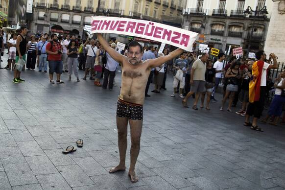 A protestor wearing a Mariano Rajoy mask and holding a banner reading