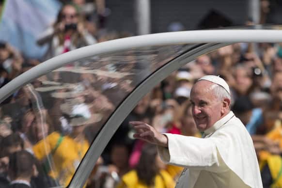 Pope Francis waves to people from his popemobile in the Gloria neighborhood as he travels to the archbishops`s palace where he`ll hold a series of meetings and public noon prayer in Rio de Janeiro, Brazil.